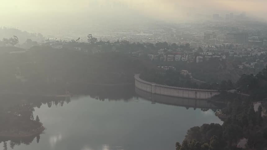 Waterfront on a river next to a metropolitan area covered in smog outdoors during dusk or dawn