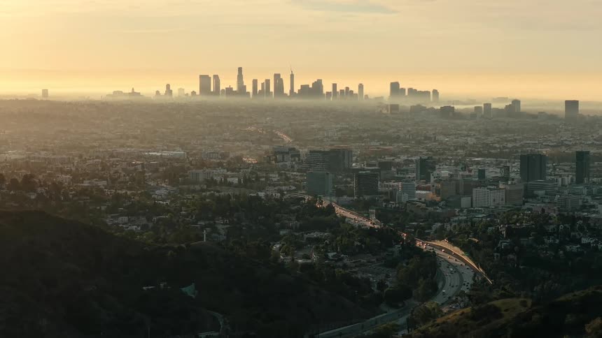 Busy freeway winding through neighborhoods toward downtown los angeles at sunset