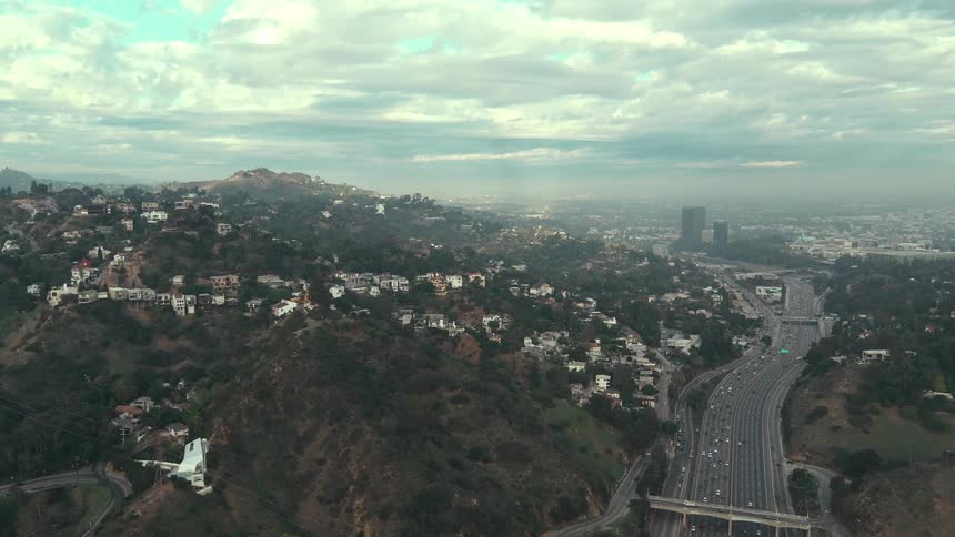 A highangle view of a city skyline and a busy feeway under a heavy layer of clouds in the distant background