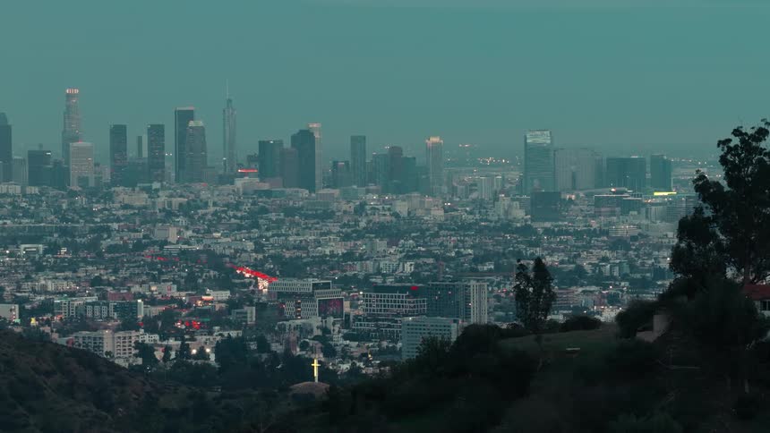 Distant view of a modern city skyline at dusk with glowing building lights under a dark teal sky