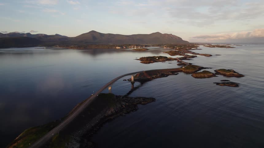 Bridge connecting islands across the water with mountains along the coast