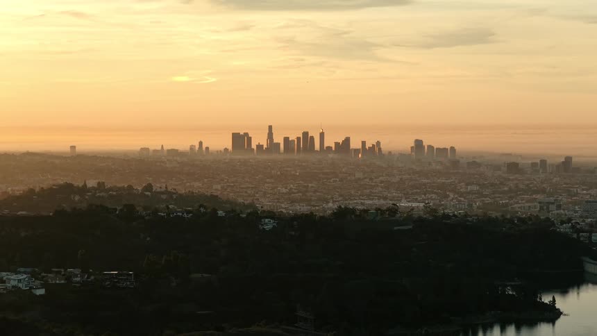 Hills and highway at sunset with view of downtown los angeles glowing in golden light