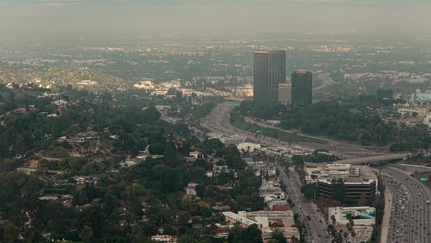 Heavy traffic on a road on a metropolitan area surrounded by many trees outdoors during dusk or dawn