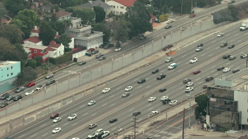 Traffic moves on the freeway and across a bridge on the overpass into the neighborhood