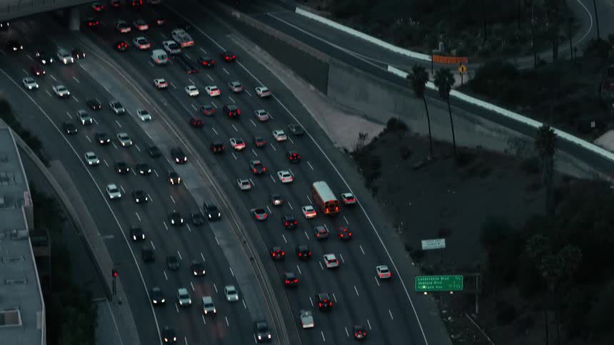Aerial view of automobiles moving in many lanes of heavy traffic on the freeway