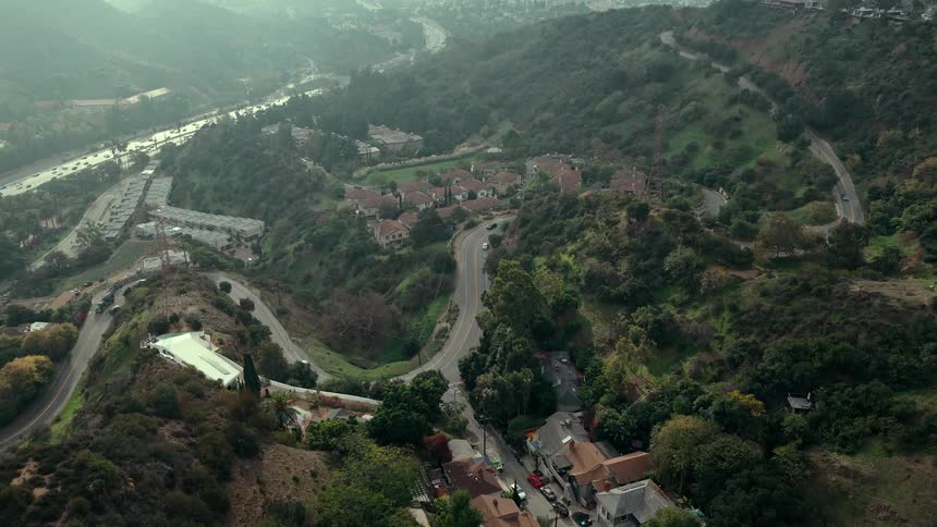 A curved road winds through a rural community at midday rising and dipping over gentle hills under the bright sun