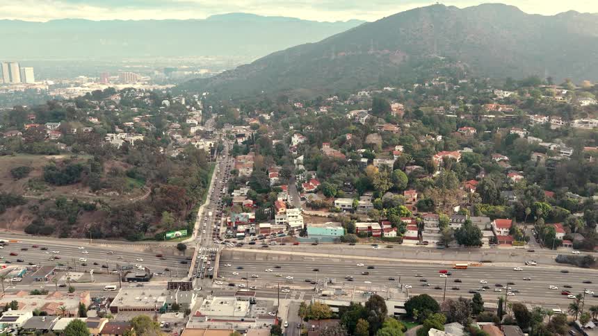 Busy highway crossing leafy neighborhood with city skyline in the distance
