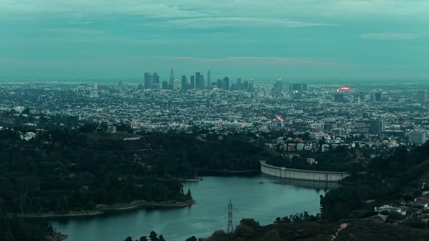 Metropolitan city next to a river surrounded by hills outdoors during dusk or dawn