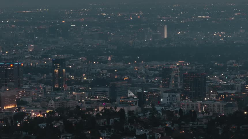 Urban landscape lit at nightfall with tall buildings and densely packed streets