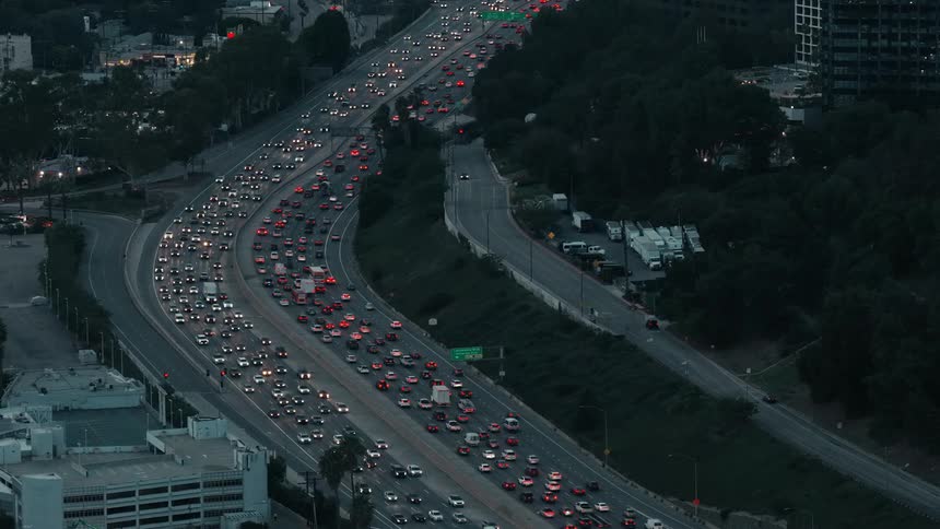 Traffic on a road surrounded by trees and buildings on a metropolitan area outdoors during night time