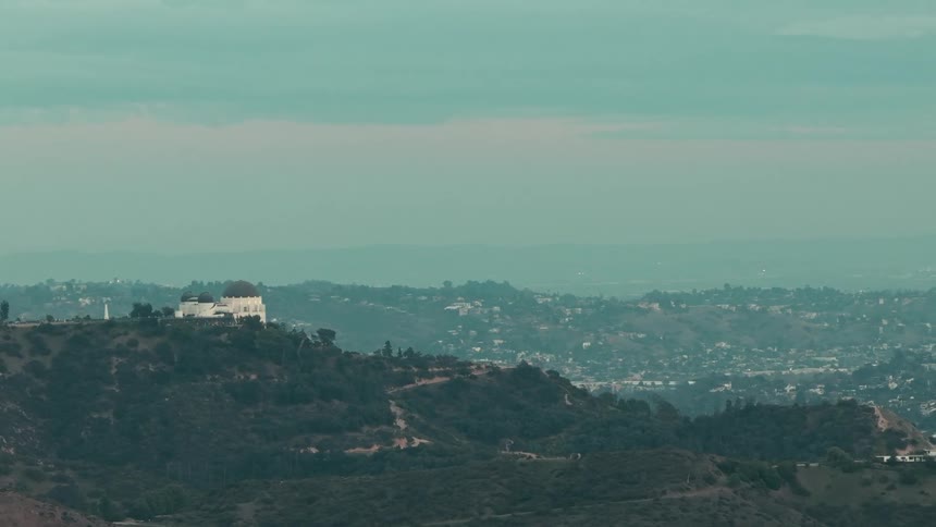 White building atop the hill facing urban sprawl across ridges
