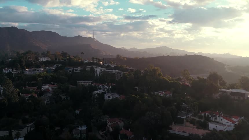 Aerial of mansions in a hillside neighborhood at sunrise