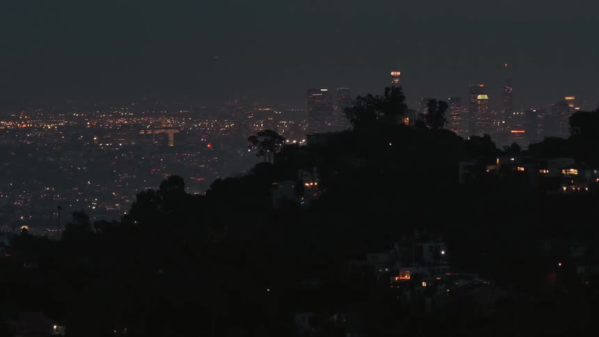 Suburban neighborhood on a hill next to a metropolitan area outdoors during night time