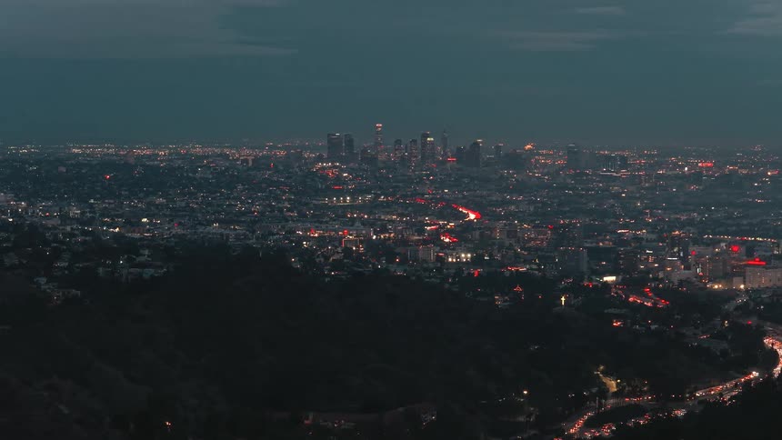 Intense vehicle flow lighting the highway against los angeles nighttime skyline