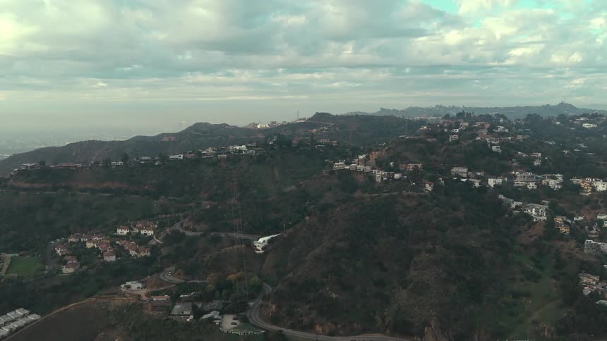 Houses and buildings across the mountainside as traffic moves on the highway
