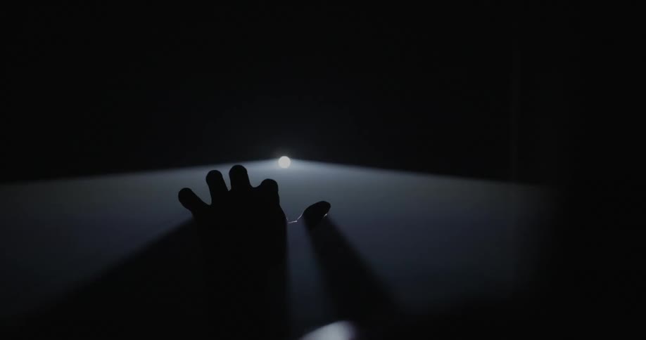 A person sticks their hand through a light projection