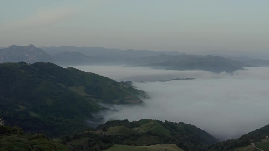 Thick fog fills the forested mountain valley