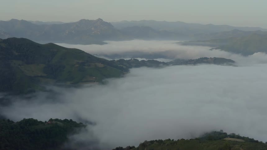 Aerial of mountain range with thick layer of fog at dawn