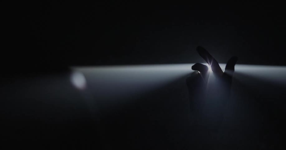 Hand moving in a small crevice with a light shining behind it