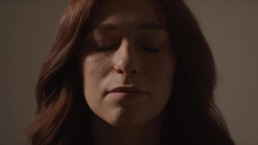 Young adult woman with a piercing on her nose with her eyes closed and then opening them indoors