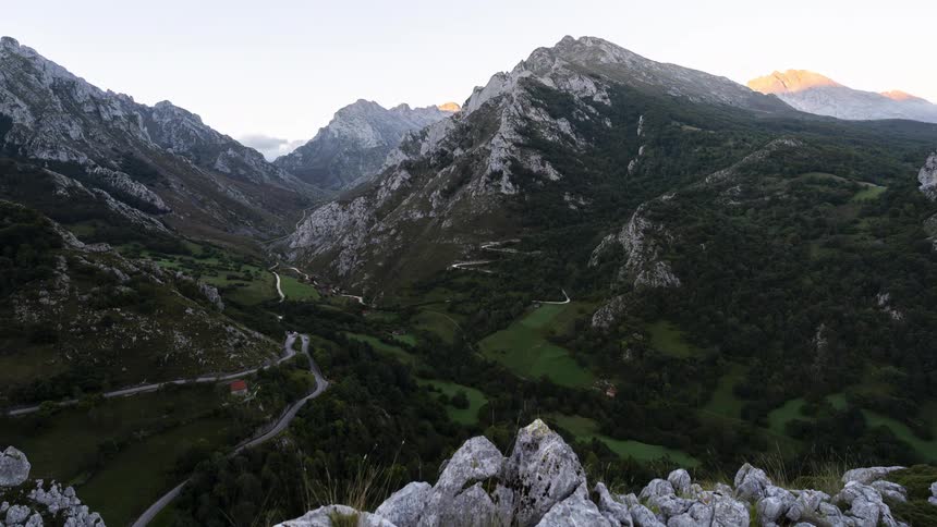 Automobiles travel on roads through the mountain valley