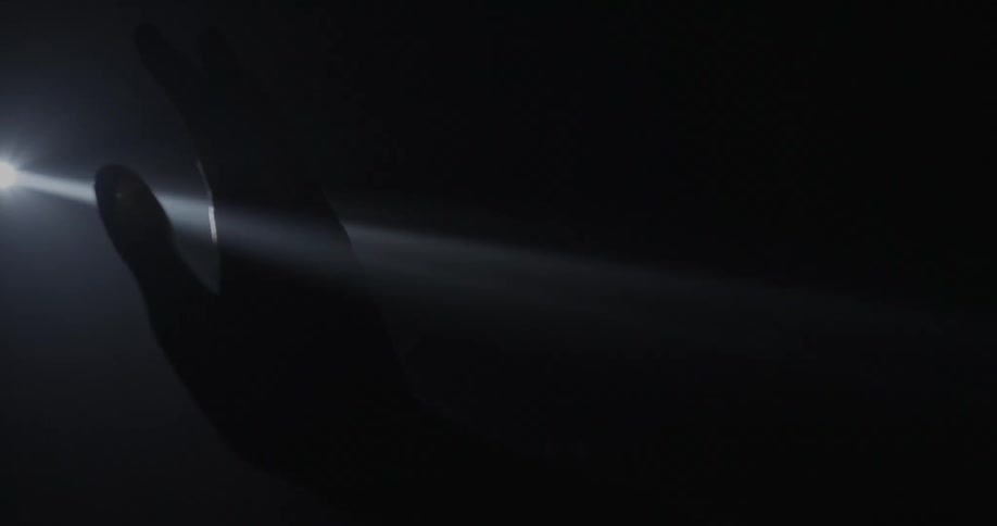 A person sticks their hand through a light projection