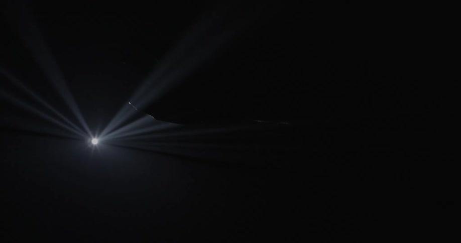 A hands plays in the rays cast by a single light