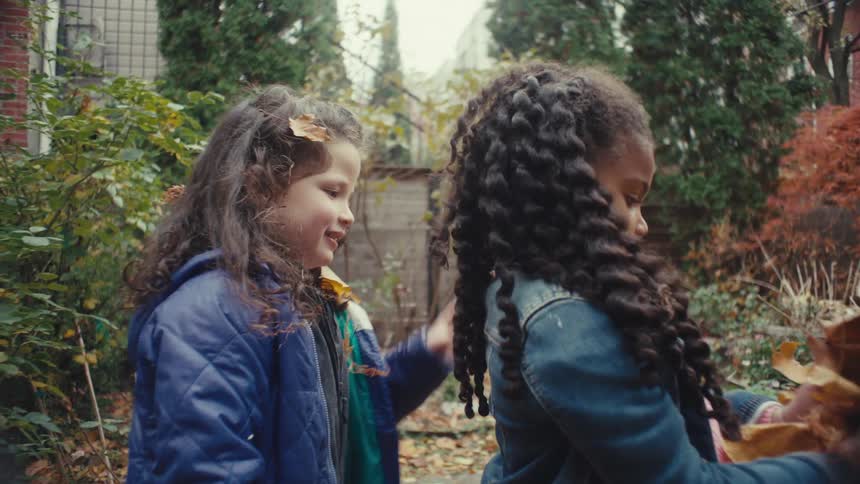 The girls play with leaves in the yard