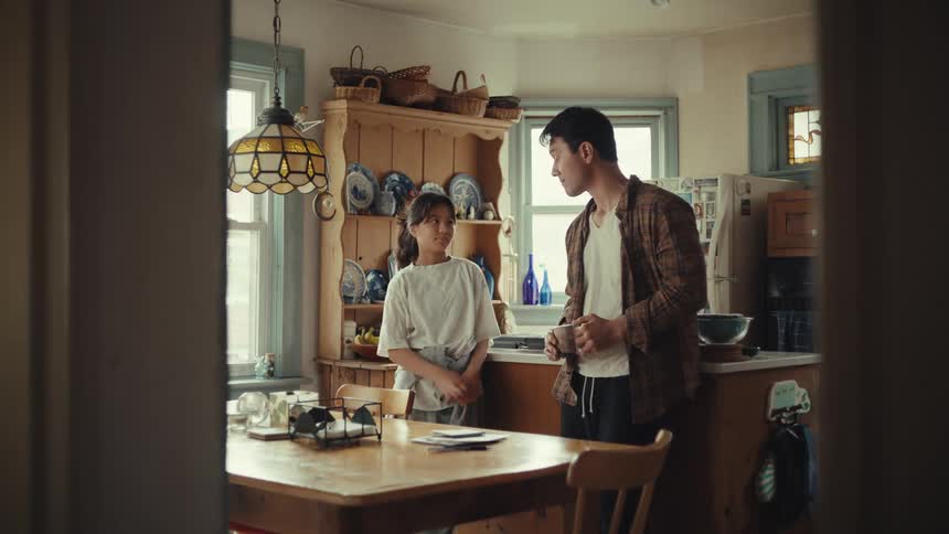 A teenager walks in the kitchen and talks with her dad