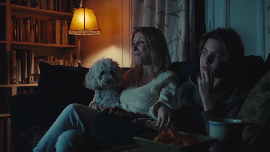 Mother and son watch television with their dog