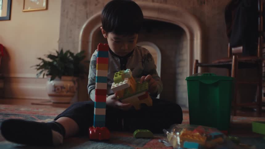 Boy sitting on a living room rug interacting with toys