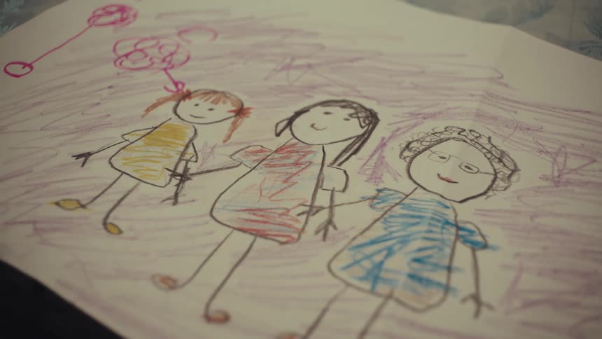 Childrens drawing shows three human figures holding hands with balloons in the background