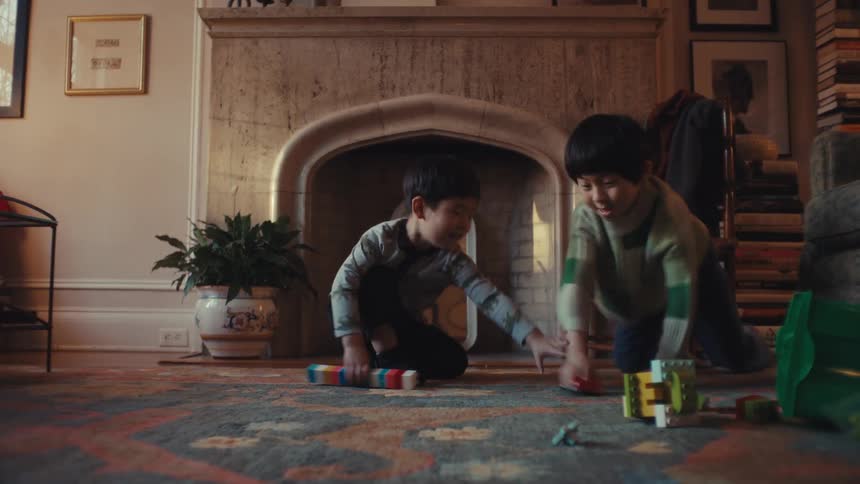 Children playing energetically on carpeted floor in cozy living room with decorative fireplace