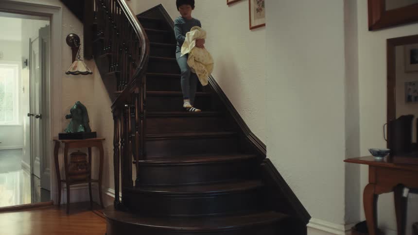 Little boy in pajamas going down the stairs of the house