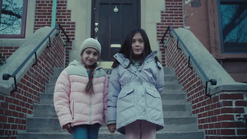 Two friends hold hands in front of the home