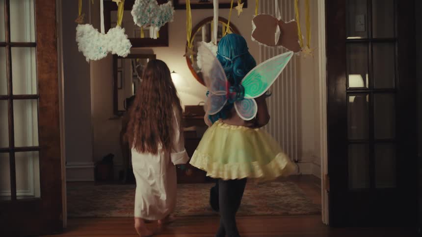 Three children dressed up in costumes playing inside the house