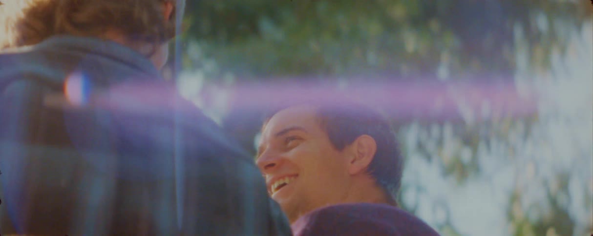 Two men are talking outside on a sunny day