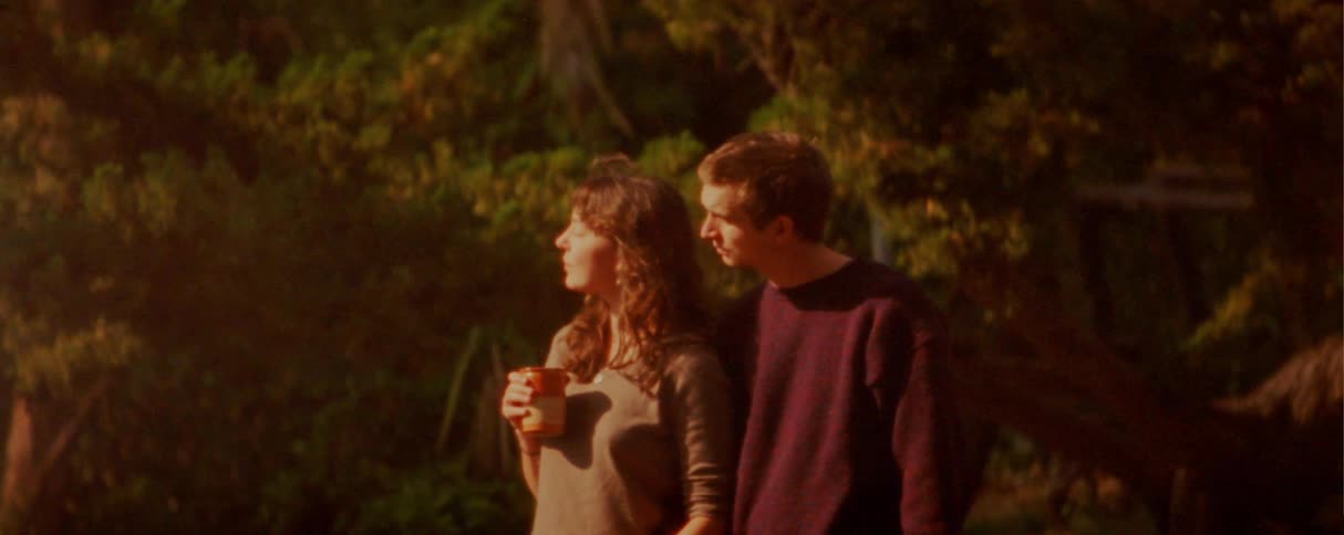 The couple hug by the trees outside
