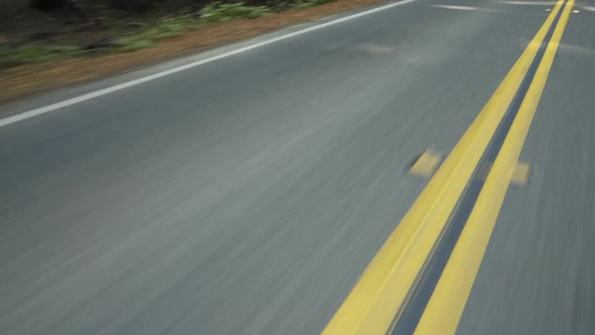 A vehicle drives on a road lined by trees