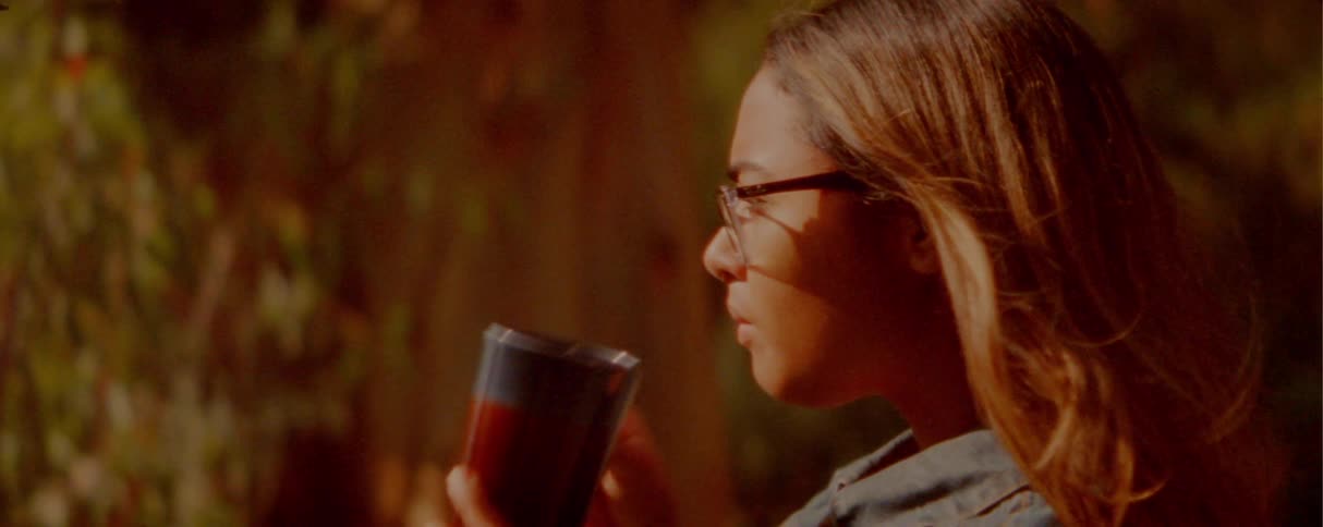 The girl drinks from her cup outside