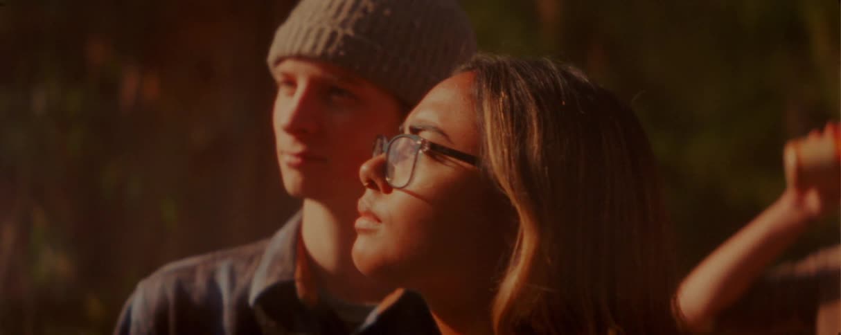 Adult people stand close together in an outdoor setting lit by warm lateafternoon light