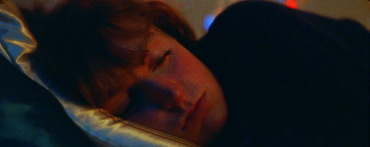 In a closeup shot a person is shown lying down and resting their head on a pillow they eventually open their eyes and look ahead with a somber or contemplative expression