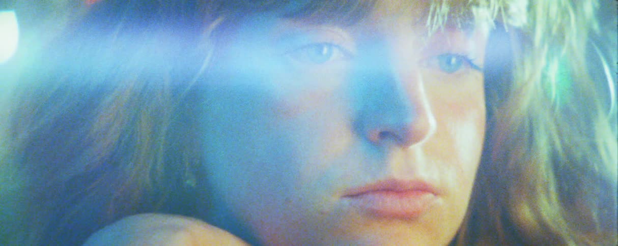 Persons face in closeup with a blue light reflection crossing the frame
