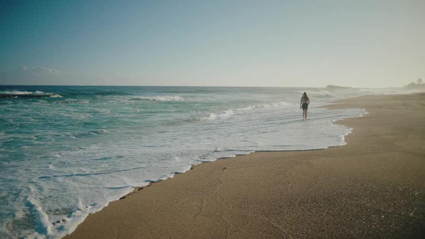 Person walking on the sand of a deserted beach