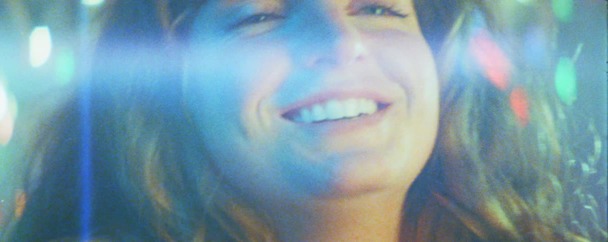 Smiling persons face in closeup with blue light reflections and defocused luminous points in the background