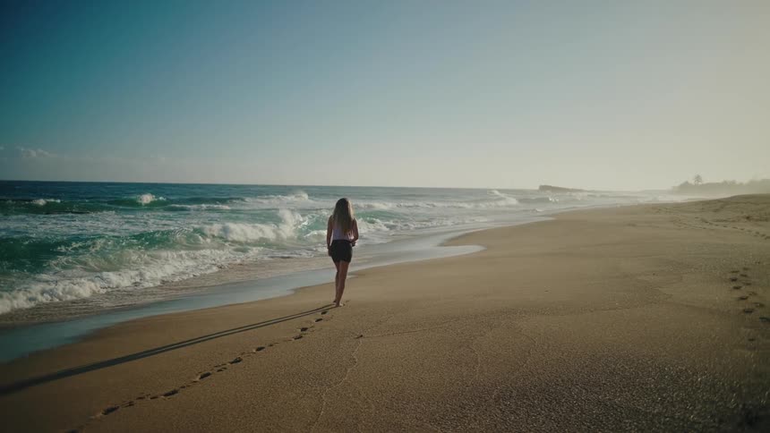 Woman walking alone on the beach sand