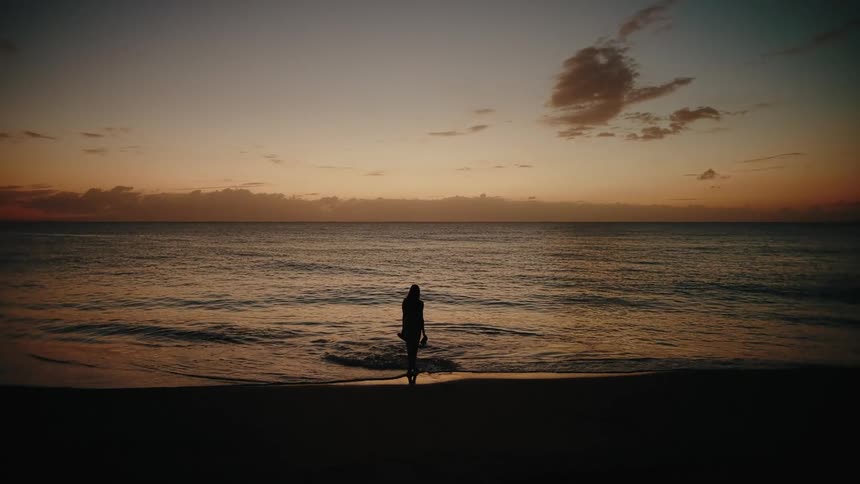 The woman walks into the water on the beach