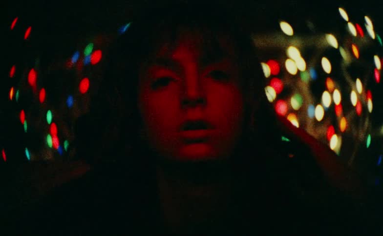 Close up portrait of a sad young woman in front of decorative lights at night