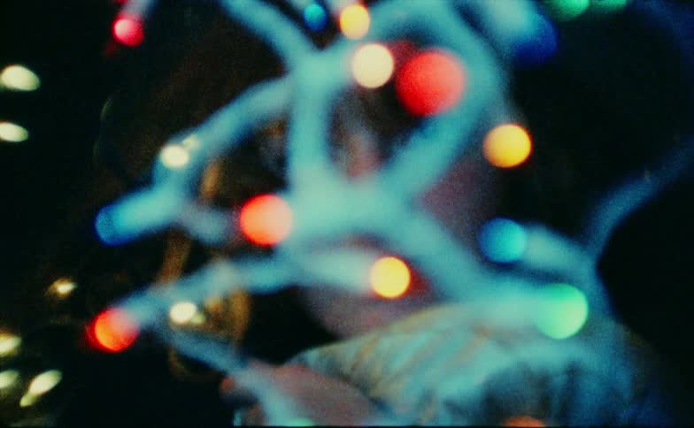 Christmas lights hang in front of the womans face