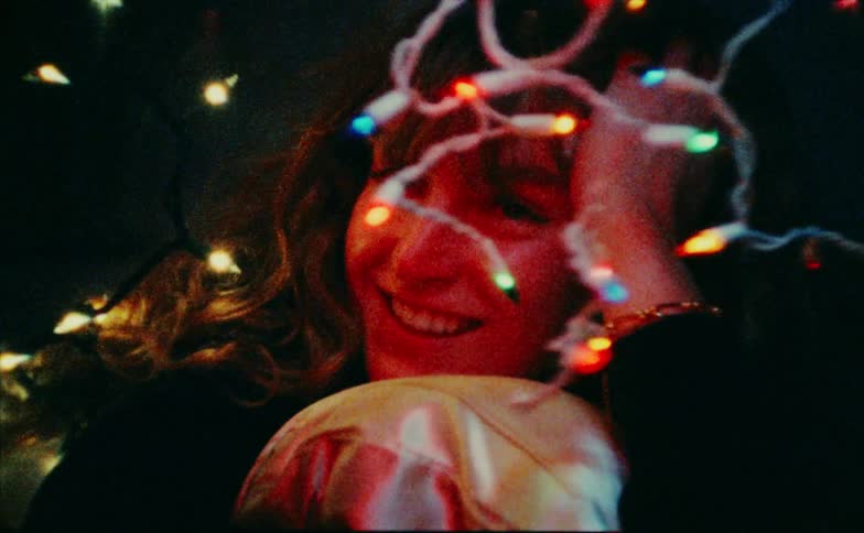 Happy woman looking at colorful christmas lights in an indoor setting